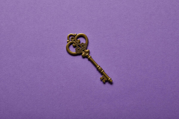 top view of vintage key on violet background