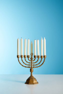 candles in menorah on blue background clipart