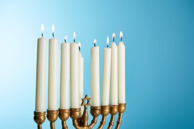 burning candles in menorah on blue background clipart