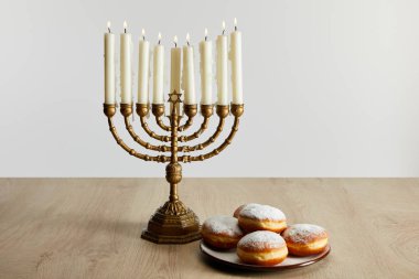 Menorah 'ta yanan mumların yanında tatlı çörekler. Hanuka' da, beyaz üzerinde izole edilmiş.