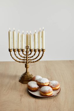 Menorah 'ta yanan mumların yanında tatlı çörekler. Hanuka' da, beyaz üzerinde izole edilmiş.