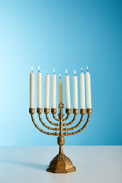 burning candles in menorah on blue background