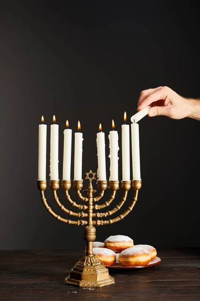 Cropped View Man Lighting Candles Menorah Doughnuts Black Background Hanukkah — Stock Photo, Image