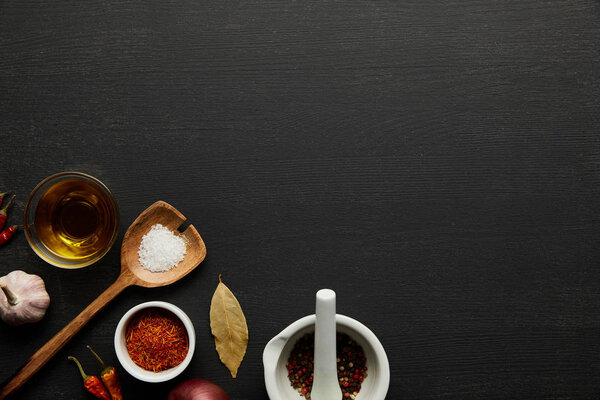 Top view of spices, salt and olive oil on black wooden background