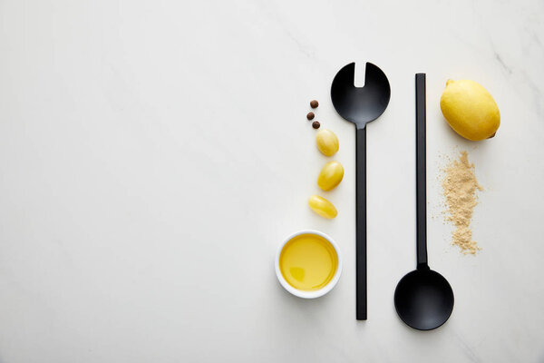 Top view of olive oil with lemon, cherry tomatoes and ladle with spoon on marble background
