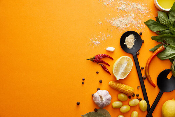 Top view of organic vegetables with basil and spices on orange background