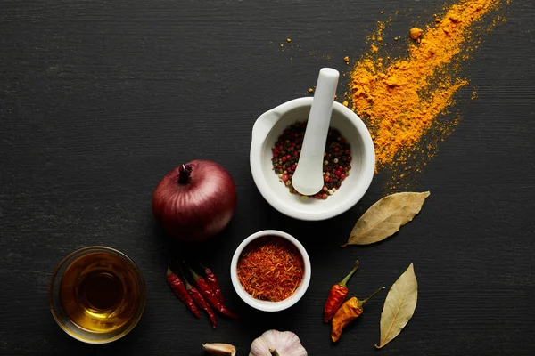 Top view of olive oil, spices with onion and garlic on black wooden background — Stock Image Top View Olive Oil Spices Onion Garlic Black Wooden Background Royalty Free Stock Photos