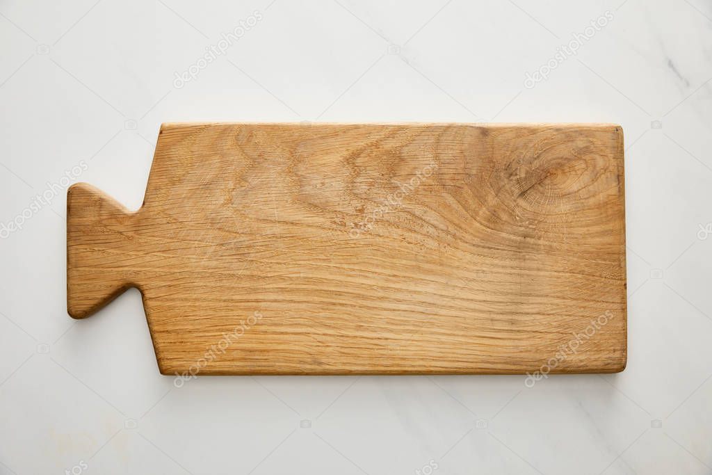 Top view of wooden cutting board on marble background