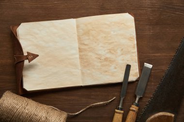 Eski marangozluk araçlarının en üst görünümü ahşap masadaki boş klasik not defterinin yanında