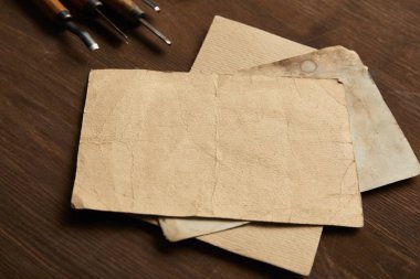 Marangozluk aletleri ahşap masadaki boş eski kağıtların yanında.