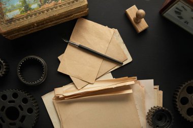 Eski viteslerin üst görünümü, pulun yanında dolmakalem, siyah yüzey üzerinde resim ve saat olan eski boş kağıt