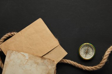 Siyah arkaplanda eski kağıt, ip ve pusula üst görünümü