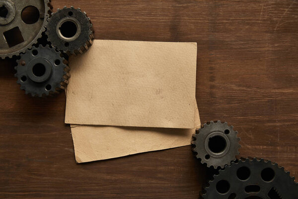 верхний вид винтажной бумаги и шестеренок на деревянный стол
