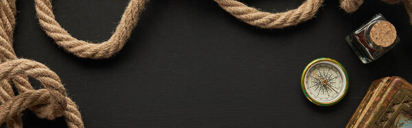 top view of vintage paper, rope, compass and painting on black background, panoramic shot