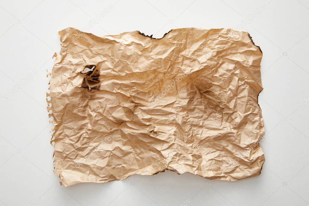top view of empty beige crumpled and burnt vintage paper on white background