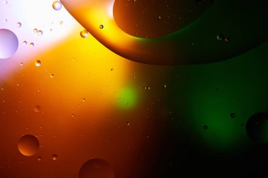 Beautiful abstract background from mixed water and oil in orange, green and purple color clipart