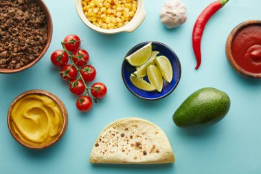 Mavi arka planda kıymalı taco malzemelerinin üst görünümü