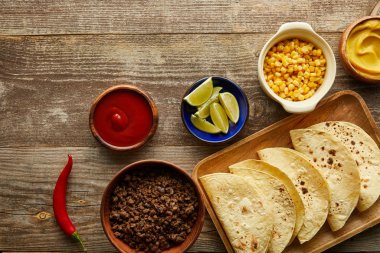 Ahşap arka planda soslu ve malzemeli taze tortilla manzarası.