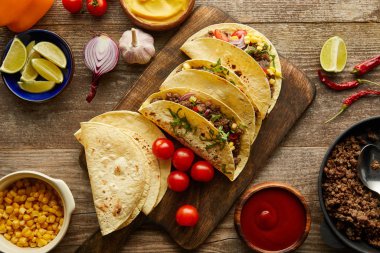 Top view of delicious tacos with minced meat and ingredients on wooden surface clipart