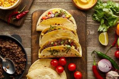 Tahta arka planda organik malzemeli geleneksel Meksika tacolarının en üst görüntüsü.