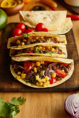 Fresh tacos with organic ingredients on wooden background clipart