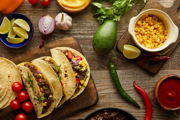 Top view of traditional mexican tacos with organic ingredients on wooden background