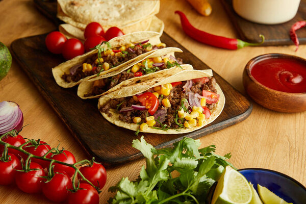 Traditional mexican tacos with vegetables and parsley on wooden table