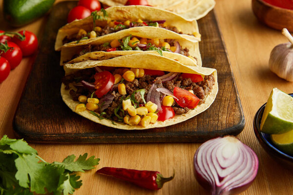 Traditional mexican tacos with ripe vegetables on wooden table