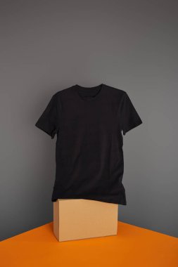 basic black t-shirt on cube on grey and orange background clipart