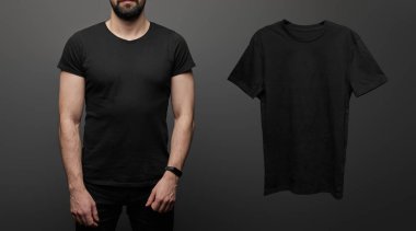 Siyah arka planda, boş siyah tişörtün yanındaki sakallı adamın kırpılmış görüntüsü.