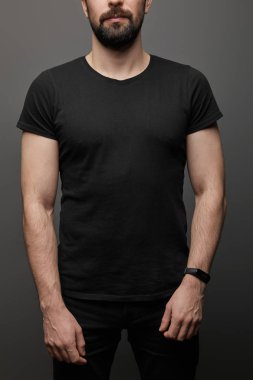 Siyah arka planda, boş siyah tişörtlü, sakallı bir adam.