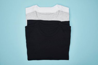 top view of blank basic black, white and grey t-shirts isolated on blue clipart