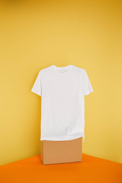 basic white t-shirt on cube on yellow background