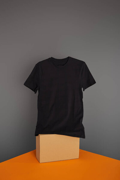 basic black t-shirt on cube on grey and orange background
