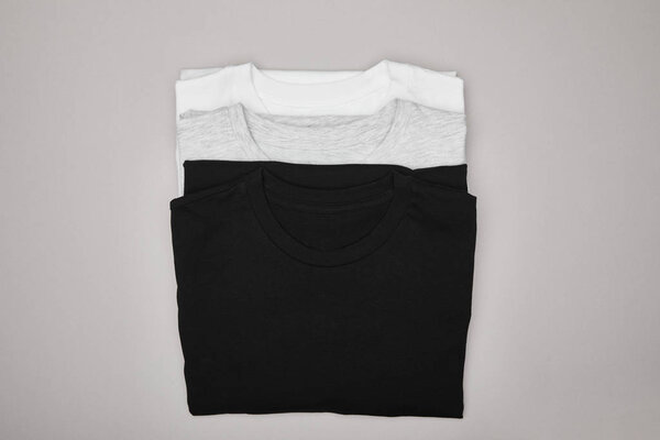 top view of blank basic black, white and grey t-shirts isolated on grey