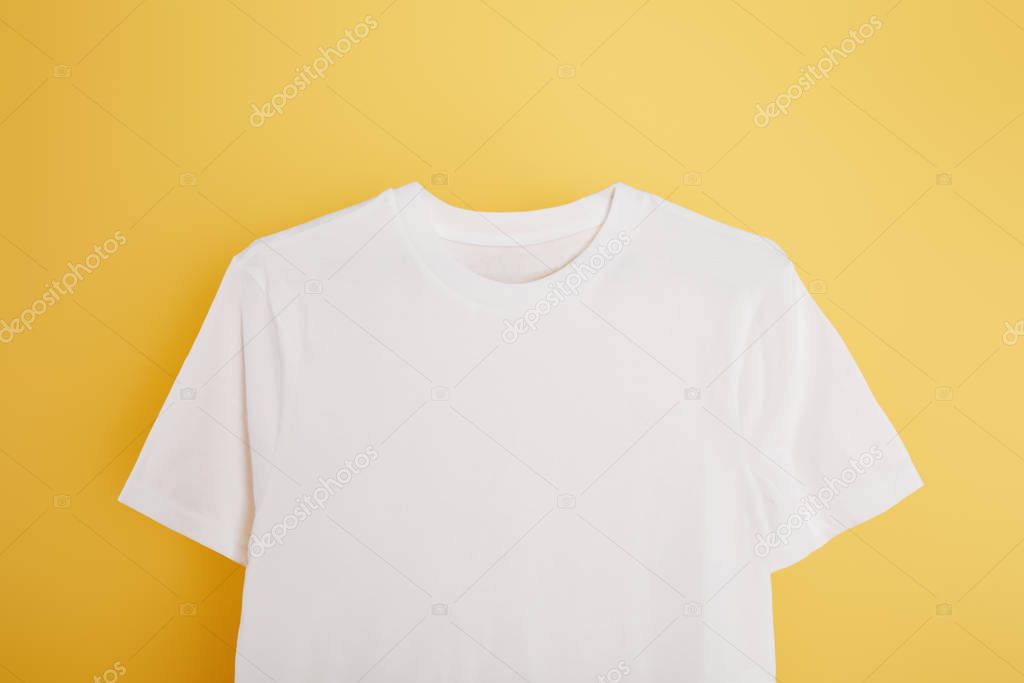 Top view of basic white t-shirt on yellow background