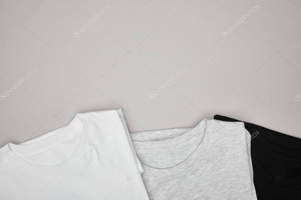 Top view of blank basic black, white and grey t-shirts isolated on grey
