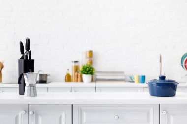 Modern beyaz mutfak. Kahve demliği, çaydanlık ve bıçaklar masanın üzerinde.