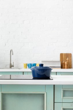 selective focus of white and turquoise kitchen interior with pot on electric induction cooktop clipart