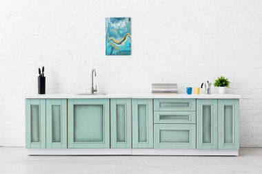 Beyaz ve turkuaz mutfak iç dekorasyonu mutfak gereçleri ve tuğla duvarda soyut resim