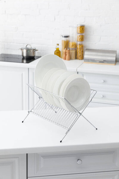 селективный фокус белых фарфоровых пластин на стенде с посудой и продовольствием возле кирпичной стены на заднем плане
