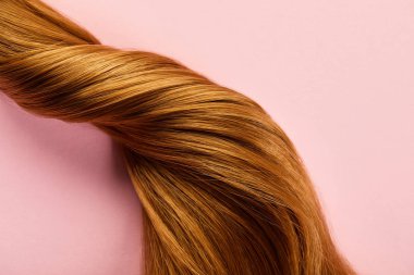 Top view of twisted brown hair on pink background clipart