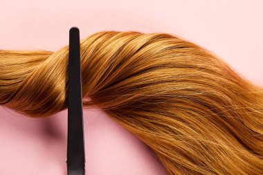 Top view of clip on twisted brown hair on pink background