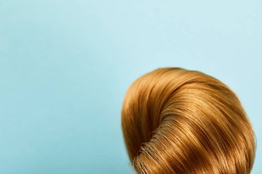 Close up view of twisted brown hair on blue background with copy space