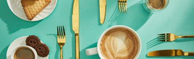 Top view of coffee with delicious cookies and cutlery on turquoise background, panoramic shot clipart