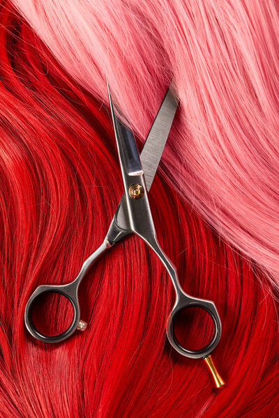 Top view of red and pink hair with scissors 