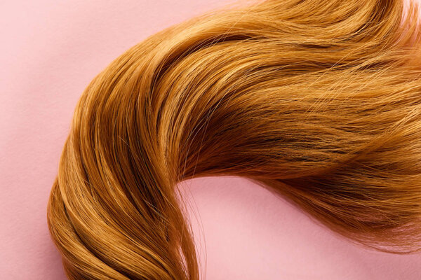 Top view of brown hair on pink background