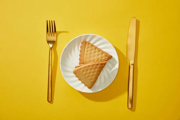 Bovenaanzicht Van Gouden Bestek Naast Smakelijke Koekjes Bord Gele Achtergrond — Stockfoto