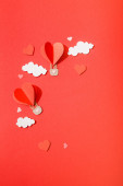 horní pohled na papírové srdce ve tvaru vzduchové balónky v mracích na červeném pozadí