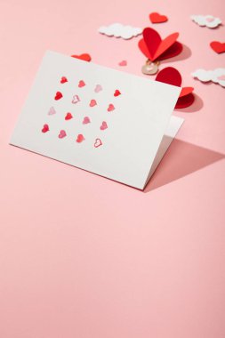 Kağıt kalpli tebrik kartının seçici odak noktası pembe bulutlardaki hava balonları şeklinde.